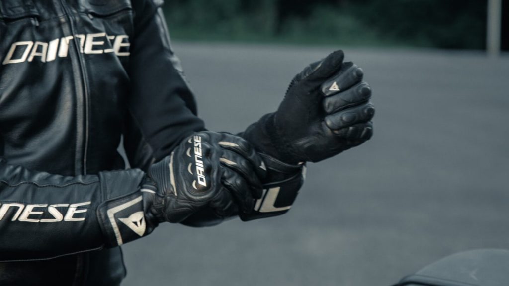 An individual putting on specialized motorcycle gloves for added protection.